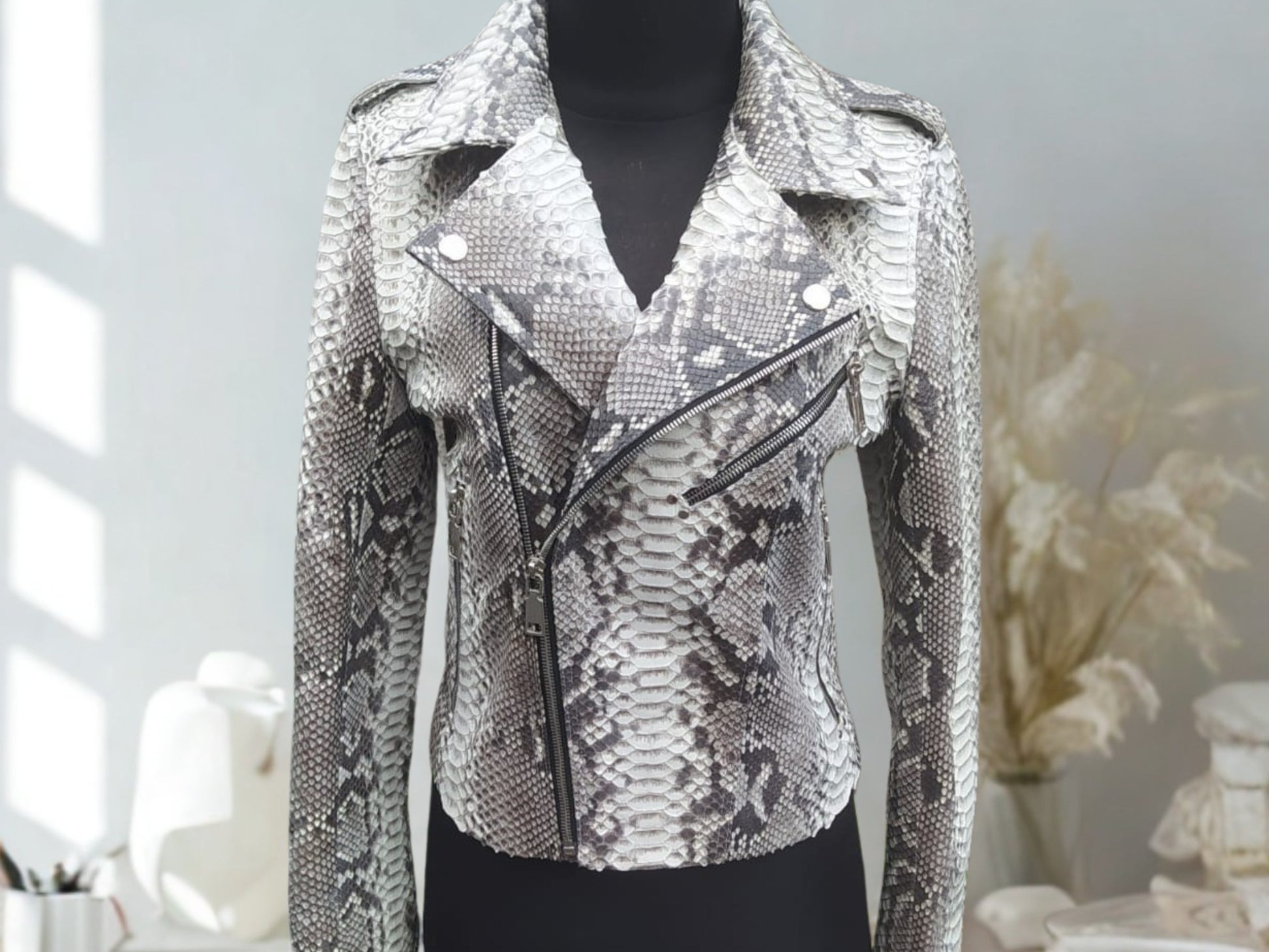 Silver snake jacket on a mannequin against a neutral background